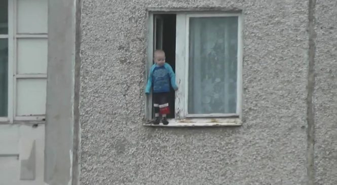 Un enfant joue sur le bord d’une fenêtre au 8ème étage d’un immeuble