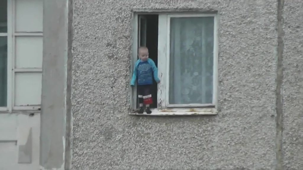 Un enfant joue sur le bord d’une fenêtre au 8ème étage d’un immeuble