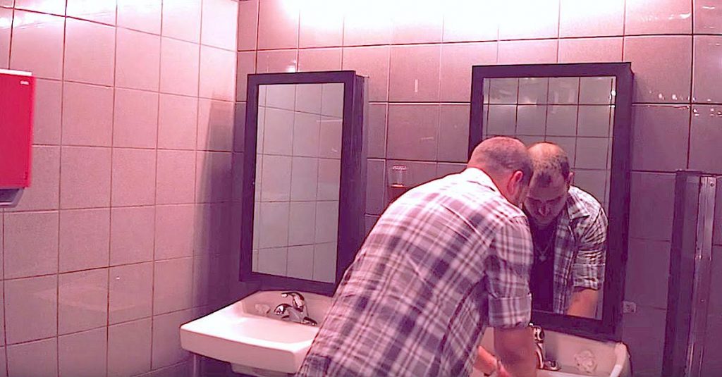 Il est dans les toilettes d’une boîte de nuit. Maintenant, regardez ce qu’il voit apparaître dans le miroir. WOAH !