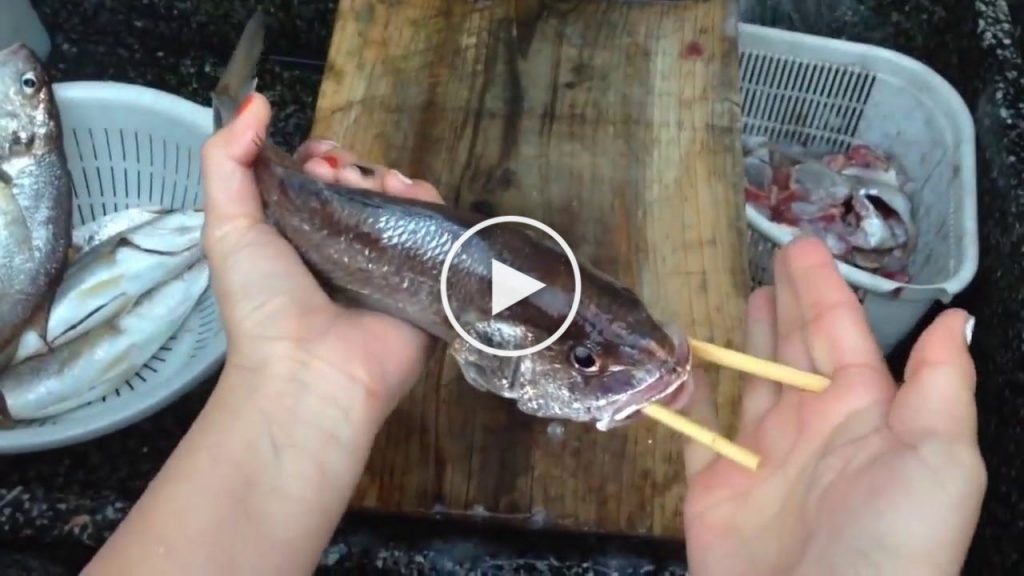 Elle vide un poisson à l’aide de seulement deux baguettes en bois
